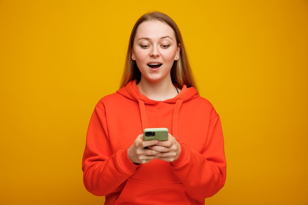 Excited young blonde woman using mobile phone 