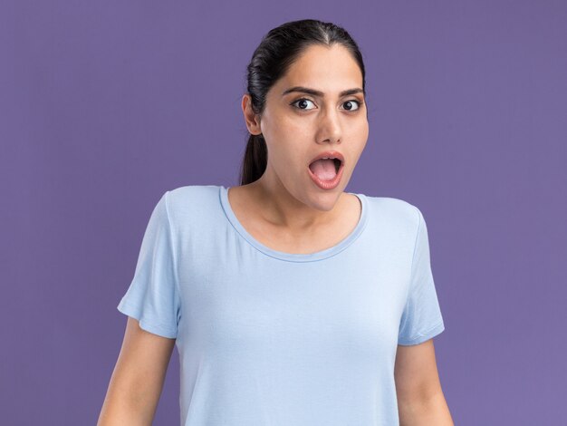 Excited young brunette caucasian girl looking at camera on purple