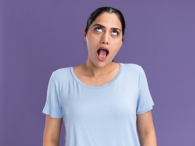 Excited young brunette caucasian girl looking up on purple