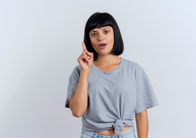 Excited young brunette caucasian woman points up