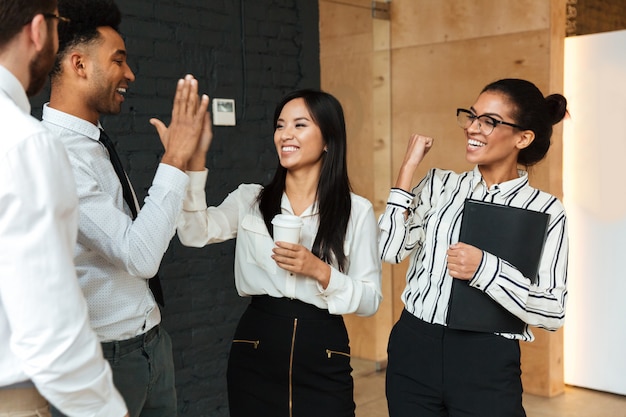 Excited young business colleagues gives a high-five to each other.