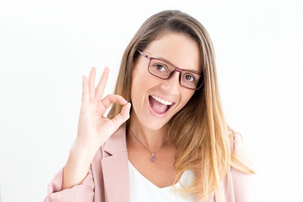 Excited young businesswoman showing ok gesture