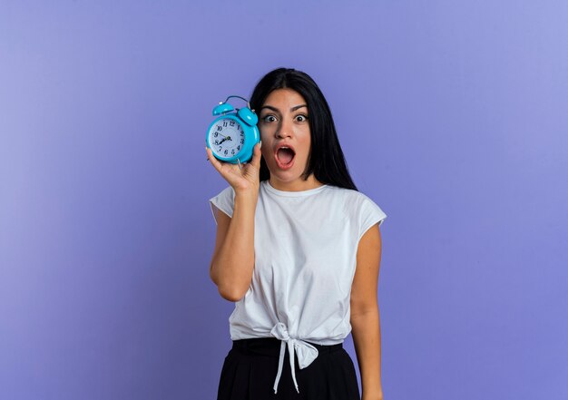 Excited young caucasian woman holds alarm clock