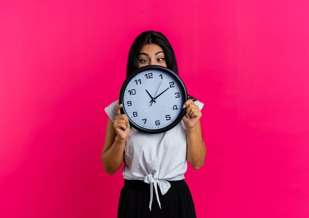 Excited young caucasian woman holds and looks at clock