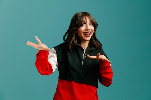 Excited young caucasian woman keeping hands in air looking at camera isolated on blue background