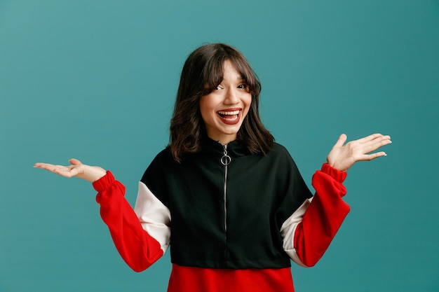 Excited young caucasian woman looking at camera showing empty hands isolated on blue background
