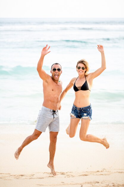 Excited young couple jumping together on beach