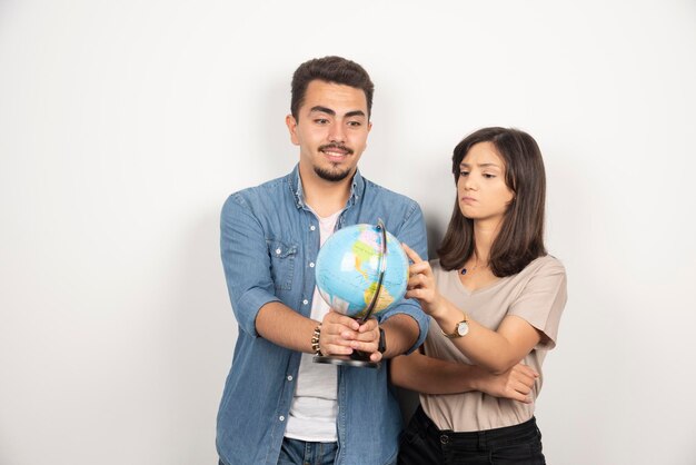 Excited young couple looking on earth globe.