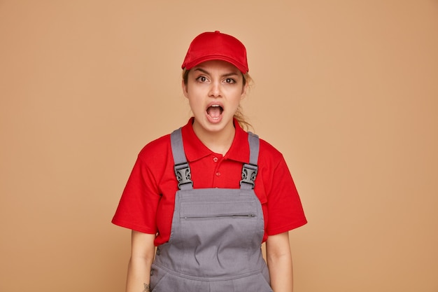 Возбужденная молодая женщина-строитель в униформе и кепке
