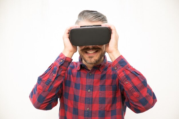 Возбужденный молодой парень держит гарнитуру VR