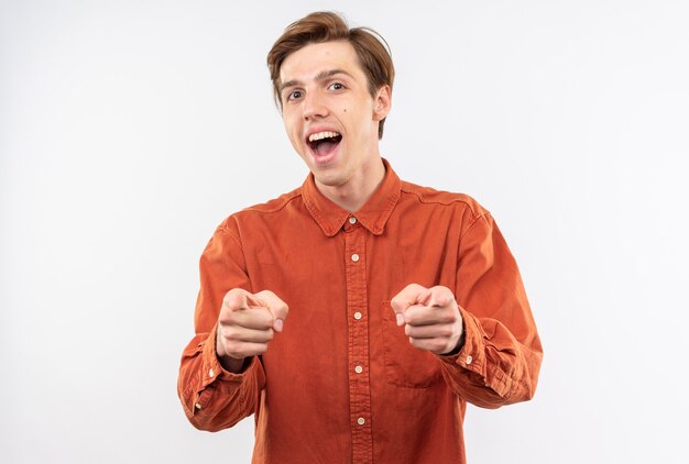 Excited young handsome guy wearing red shirt points at camera 