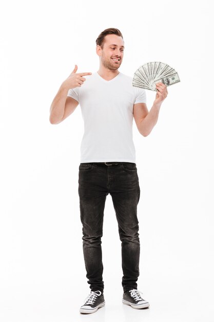 Excited young man pointing and holding money.