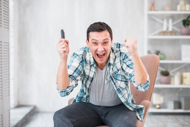 Excited young man with joystick triumphing with raised hands