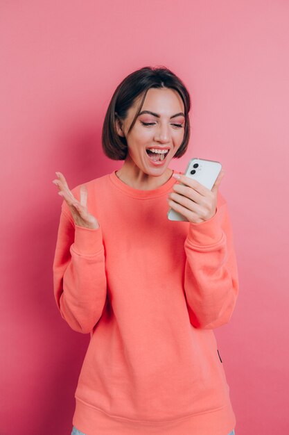 Возбужденная молодая женщина, пораженная невероятным сообщением о продаже мобильного приложения для покупок, смотрит на смартфон, девушка-победитель, держащая сотовый телефон, кричит от радости
