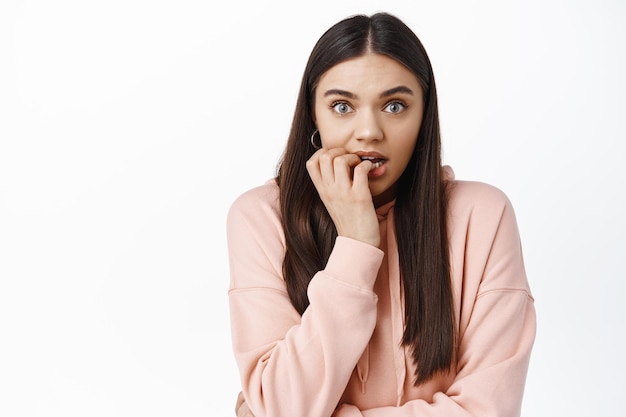 Excited young woman biting fingers and staring at front with temptation and excitement, anticipating something, watching interesting moment