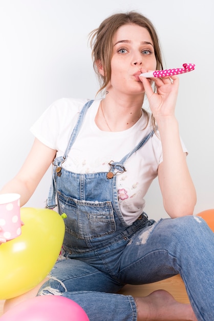 Excited young woman blowing party horn