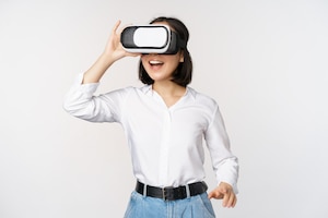 Excited young woman enter virtual reality in her glasses asian girl using vr headset standing over white background