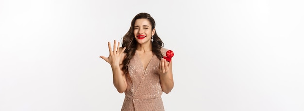 Free photo excited young woman in glamour dress being engaged showing finger with ring and looking happy