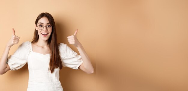 Free photo excited young woman in glasses showing thumbs up and smiling praising good optic store approve and l