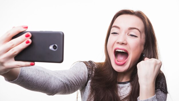 휴대 전화를 통해 셀카 사진을 만드는 흥분된 젊은 여성