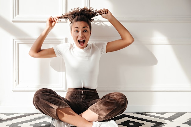 Excited young woman playing with curly hair