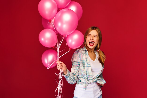 Excited young woman posing with pink air balloons