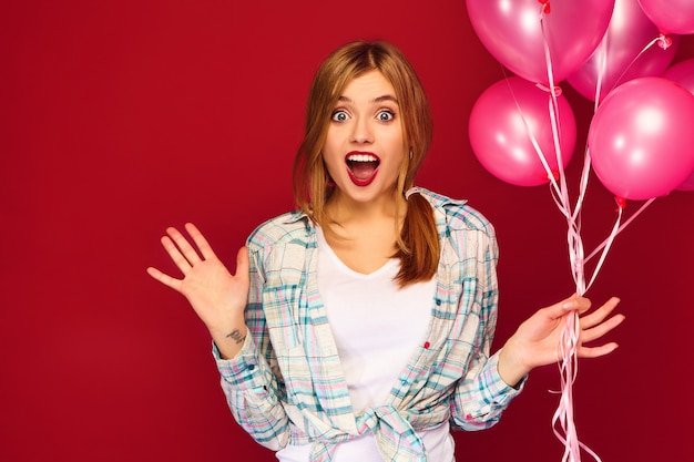 Excited young woman posing with pink air balloons