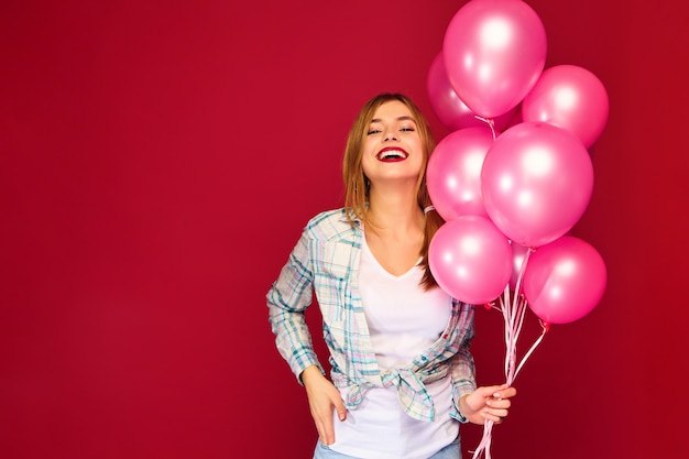 Excited young woman posing with pink air balloons