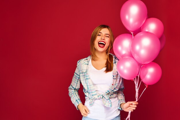 Giovane donna emozionante che posa con gli aerostati rosa