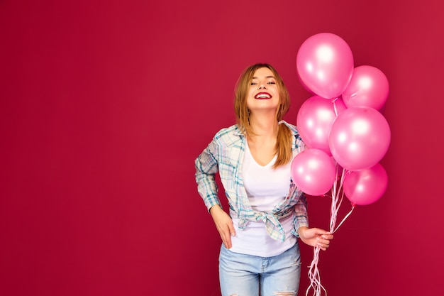 Взволнованная молодая женщина позирует с розовыми воздушными шарами
