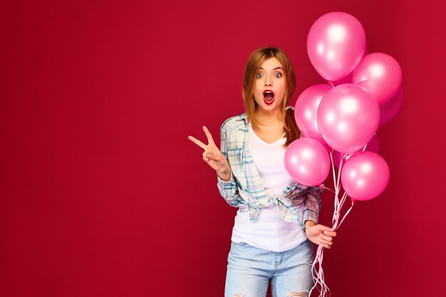 興奮した若い女性がピンクの気球でポーズ