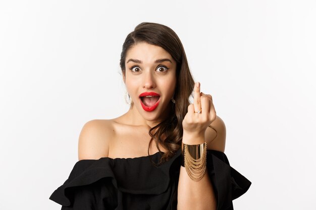 Excited young woman showing finger with engagement ring, got engaged, she said yes, standing over white background