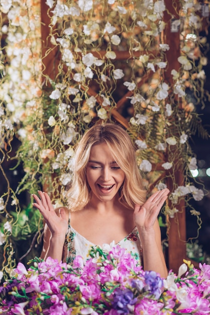 Excited young woman standing in front of creeper looking at beautiful flower bouquet