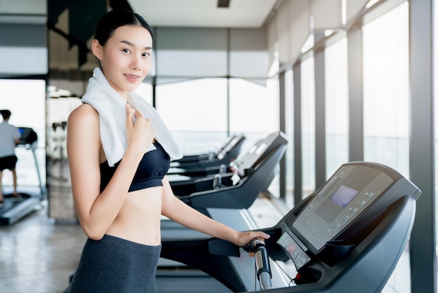 Exhausted asian female girl standing on the treadmill in the gym relax and cooldown healthy ideas concept