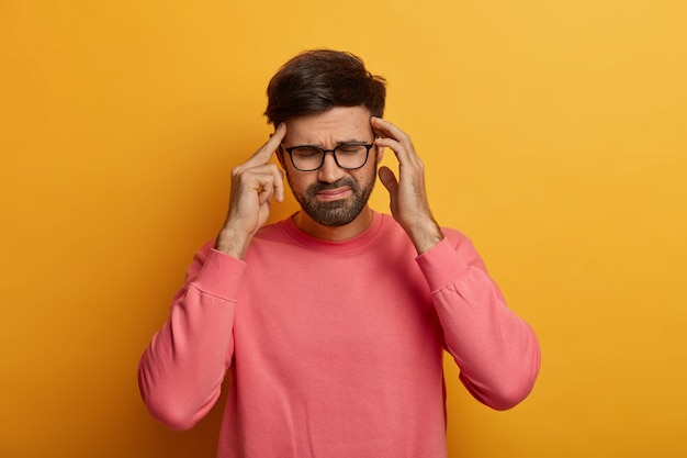 Exhausted bearded man suffers from unbearable headache