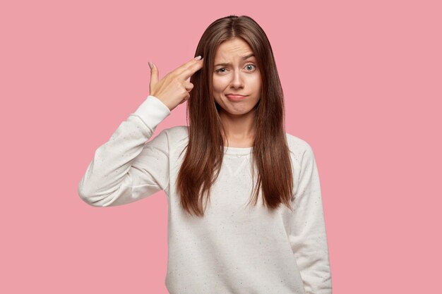 Exhausted beautiful brunette posing against the pink wall