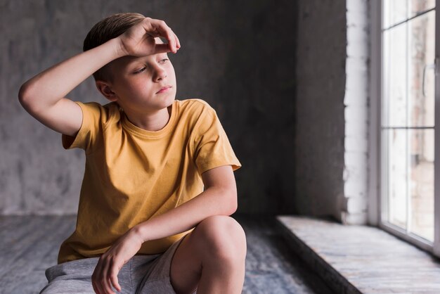 Exhausted boy with his hand on forehead