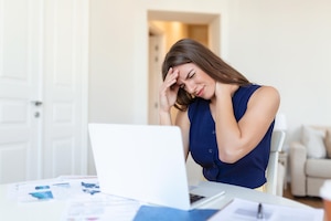 Exhausted businesswoman having a headache in home office creative woman working at office desk feeling tired