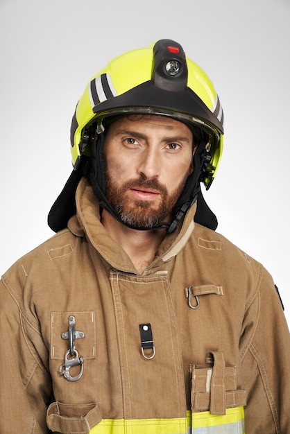 Бесплатное фото Уставший кавказский пожарный в шлеме устало смотрит в камеру в помещении, портрет усталого