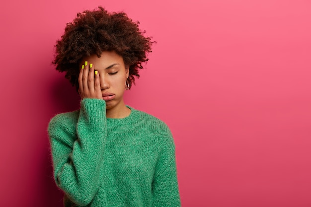 Free photo exhausted dark skinned woman covers half of face, feels tired after working all night