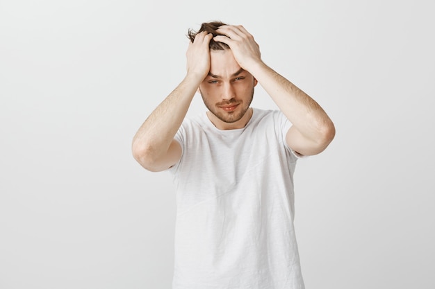 Exhausted and distressed young man grab head and looking tired