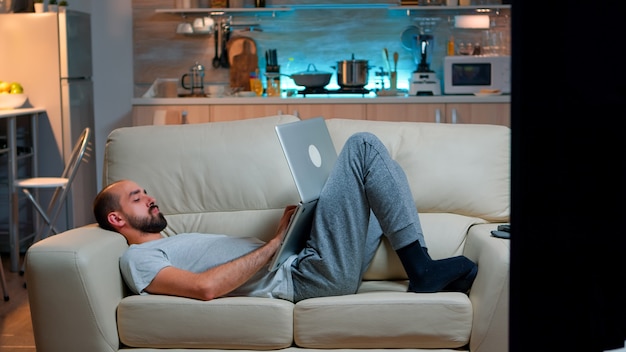 Exhausted man falling asleep while working on internet communication project