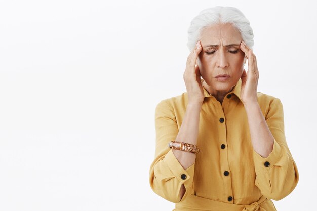 Exhausted senior woman touch head, complaining on migraine, have headache