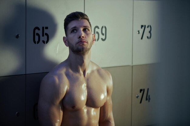 Exhausted sportsman resting in locker room after training and thinking of something