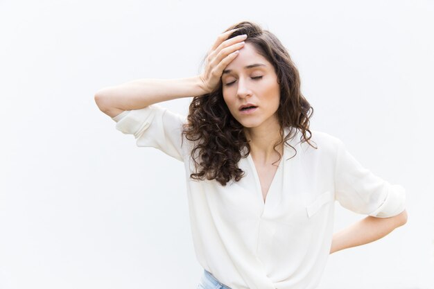 Exhausted tired woman with closed eyes touching head