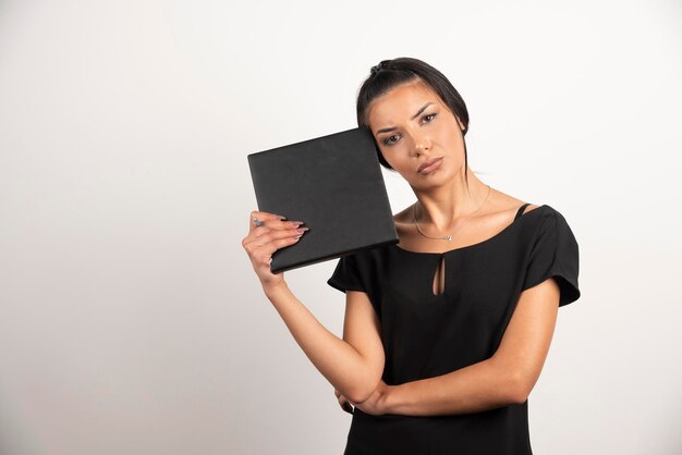 Exhausted woman employee with notebook looking at camera.