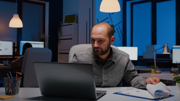 Free photo exhausted workaholic businessman analysing marketing statistics sitting at desk table