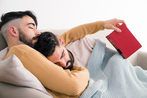 Измученная молодая пара геев спят вместе на диване