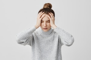 Exhausted young woman touching her head with eyes closed. female exchange worker suffering from unbearable headache. health concept