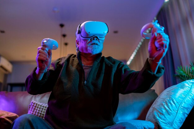 Exicetアジアのシニア老人白ひげは自宅のリビングルームで仮想拡張現実メタバースesportオンラインデジタルワールドゲームを楽しむカジュアルなリラックス老人は自宅でデジタルレジャーゲームをプレイする